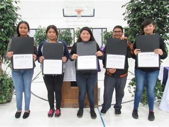 Five students showing their honor roll awards.