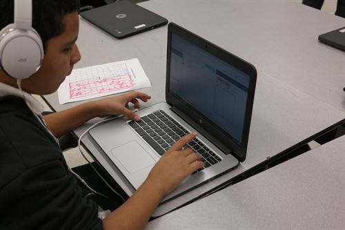 Boy with headphones on working with a laptop.