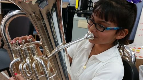 Girl sitting down playing the baritone.